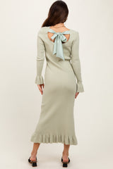 woman wearing a light green ribbed midi dress with a bow detail at the back and ruffled hem