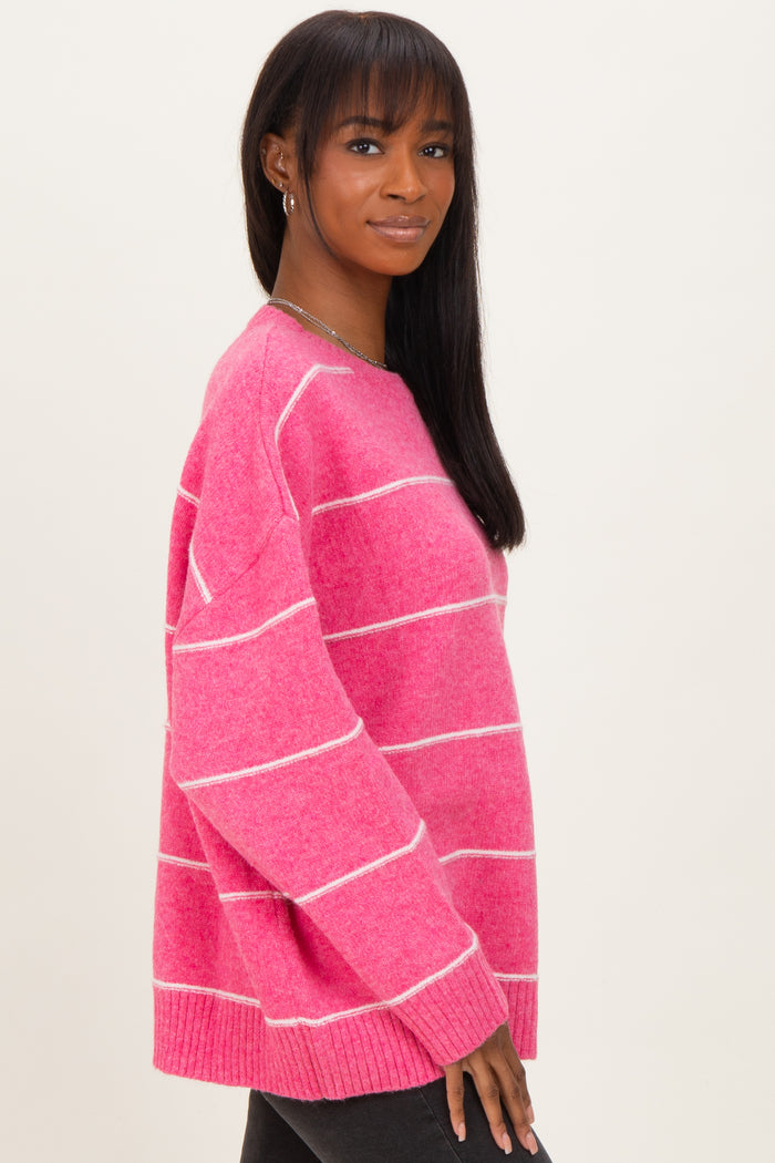 woman wearing a pink striped sweater with a relaxed fit and long sleeves