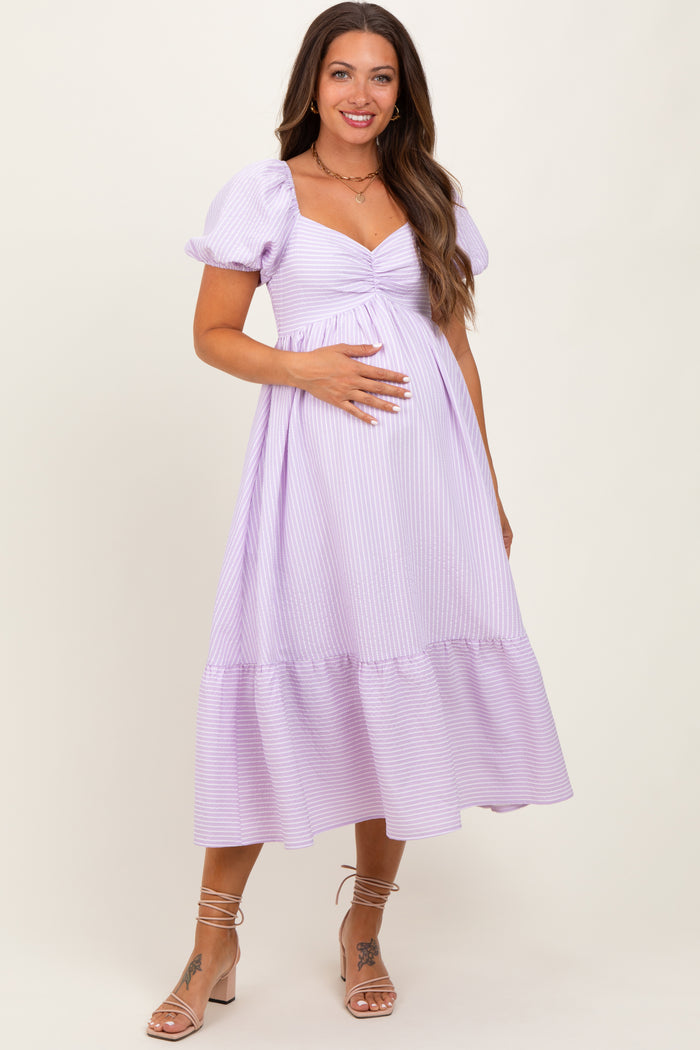 woman wearing a lavender striped maternity dress with a puff sleeve and holding her baby bump