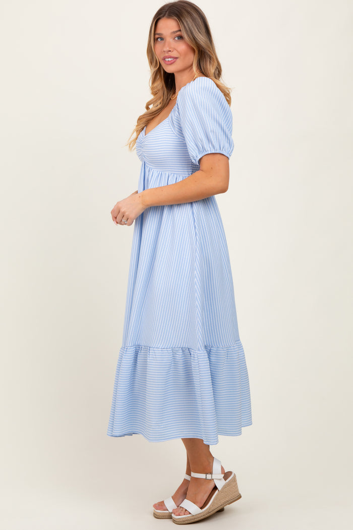 woman wearing a light blue striped puff sleeve midi dress with a tiered skirt and wedge sandals