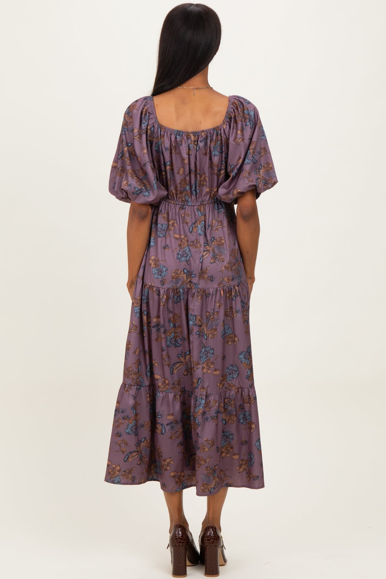woman wearing a purple floral maxi dress with puff sleeves and a cinched waist, seen from the back