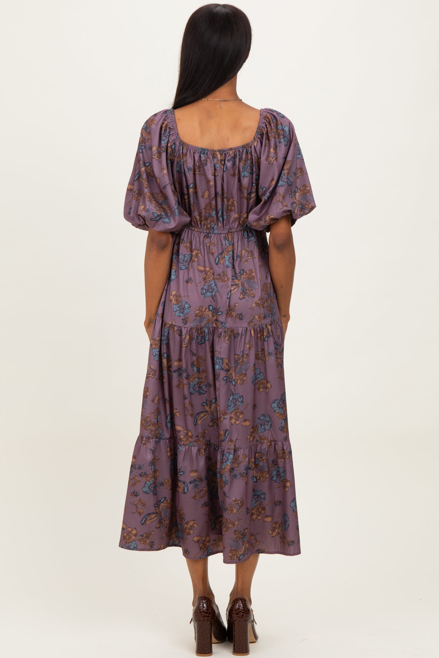 woman wearing a purple floral maxi dress with puff sleeves and a cinched waist, seen from the back