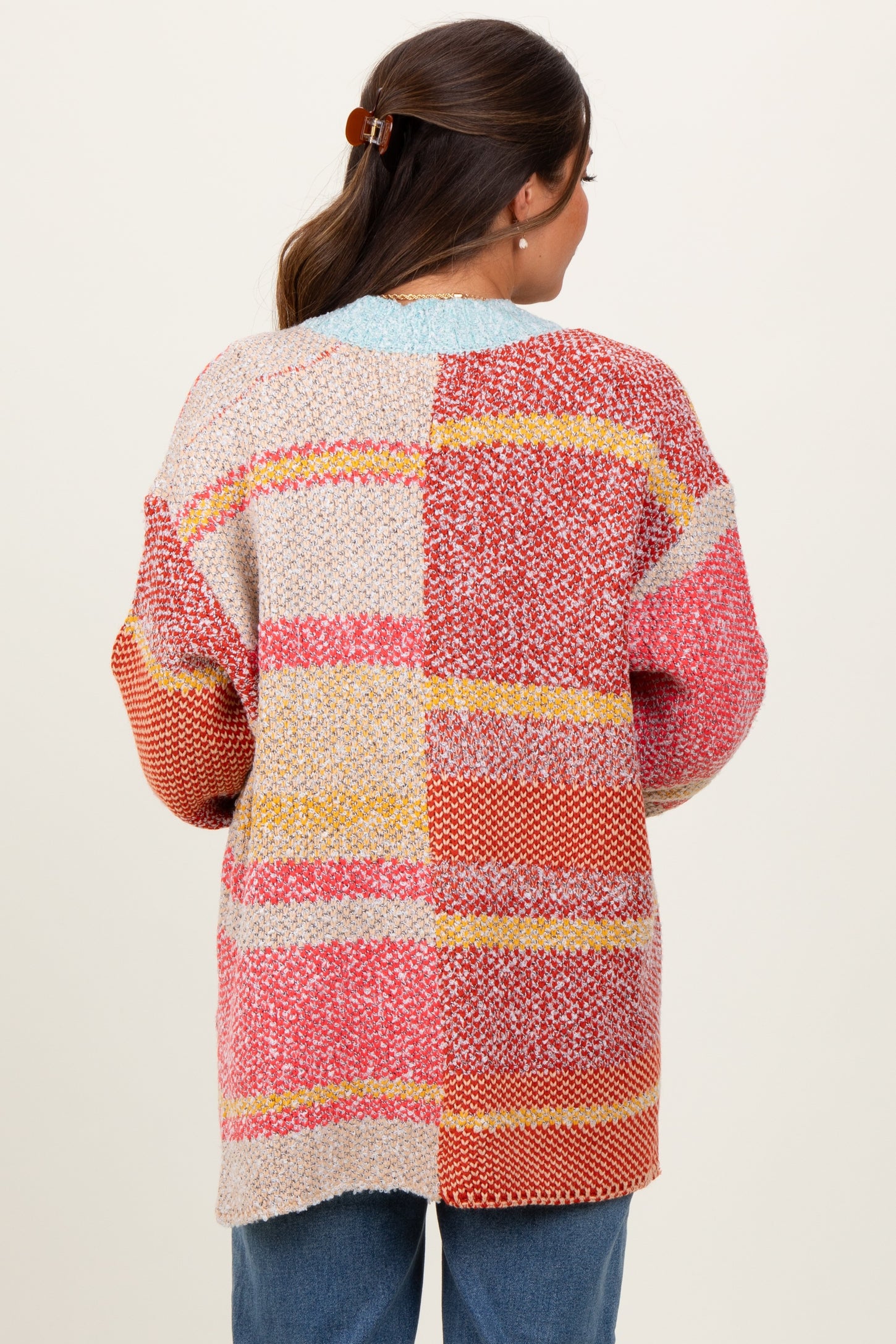 woman wearing a colorful patchwork maternity sweater, viewed from the back, with relaxed fit and loose sleeves