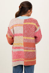 woman wearing a colorful patchwork maternity sweater, viewed from the back, with relaxed fit and loose sleeves