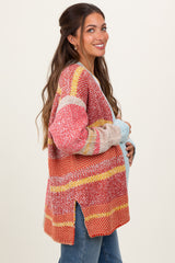 woman wearing a colorful striped maternity cardigan with side slits and a relaxed fit, showcasing her baby bump