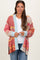 woman wearing a multicolor striped open-front maternity cardigan over a white top and jeans, holding the edges of the cardigan