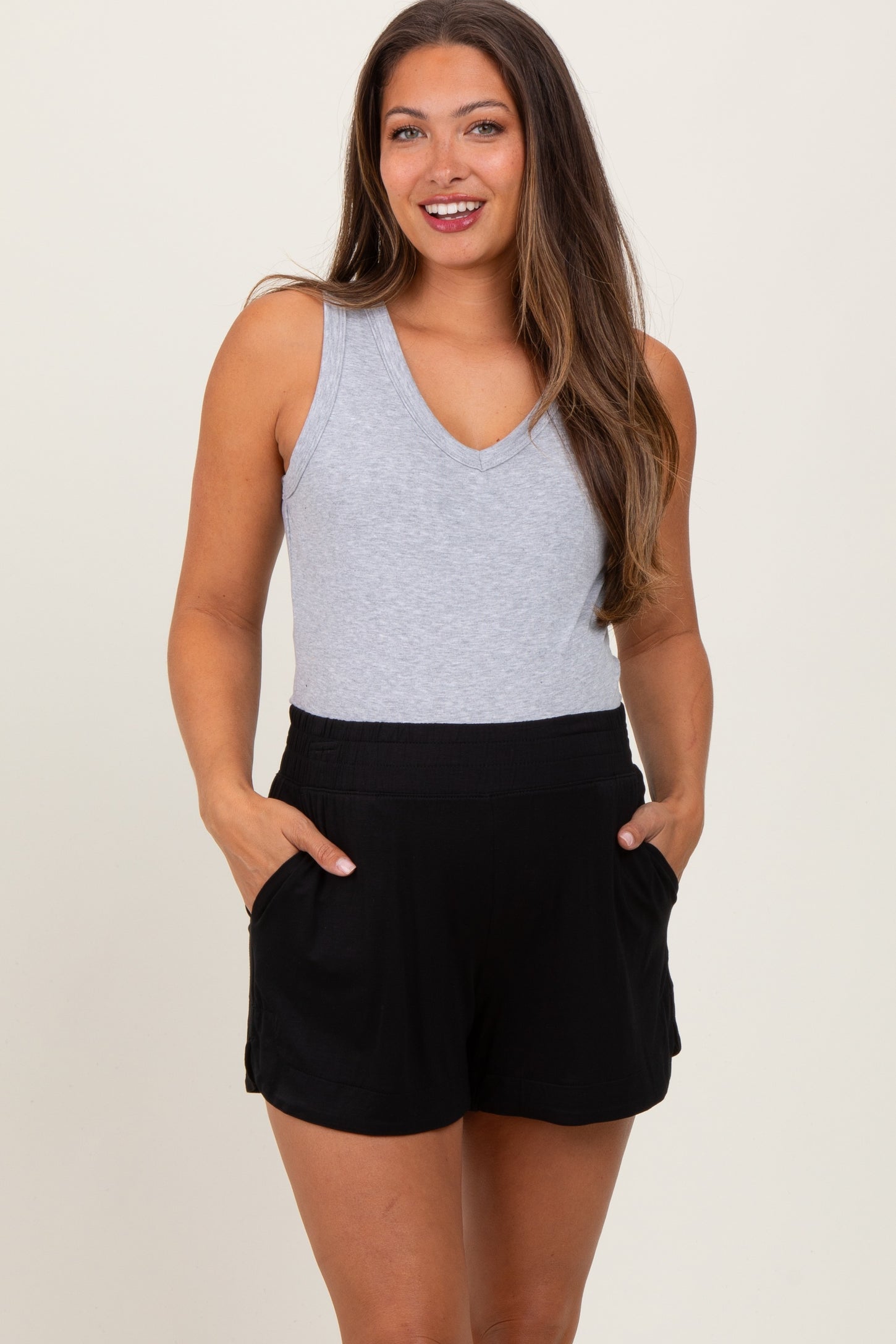 woman wearing a gray sleeveless maternity top and black maternity shorts with pockets