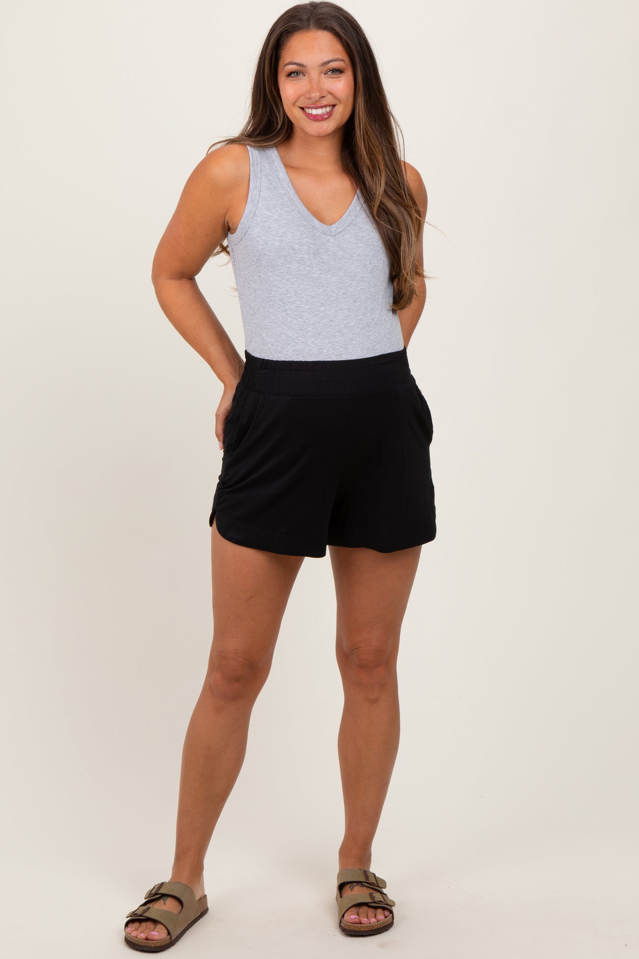 woman wearing a gray v-neck maternity tank top and black maternity shorts with pockets.