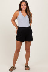 woman wearing a gray v-neck maternity tank top and black maternity shorts with pockets.