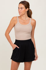 woman wearing a beige ribbed tank top and black elastic-waist shorts with side pockets