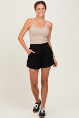 woman wearing a beige ribbed tank top and black elastic waist shorts with pockets