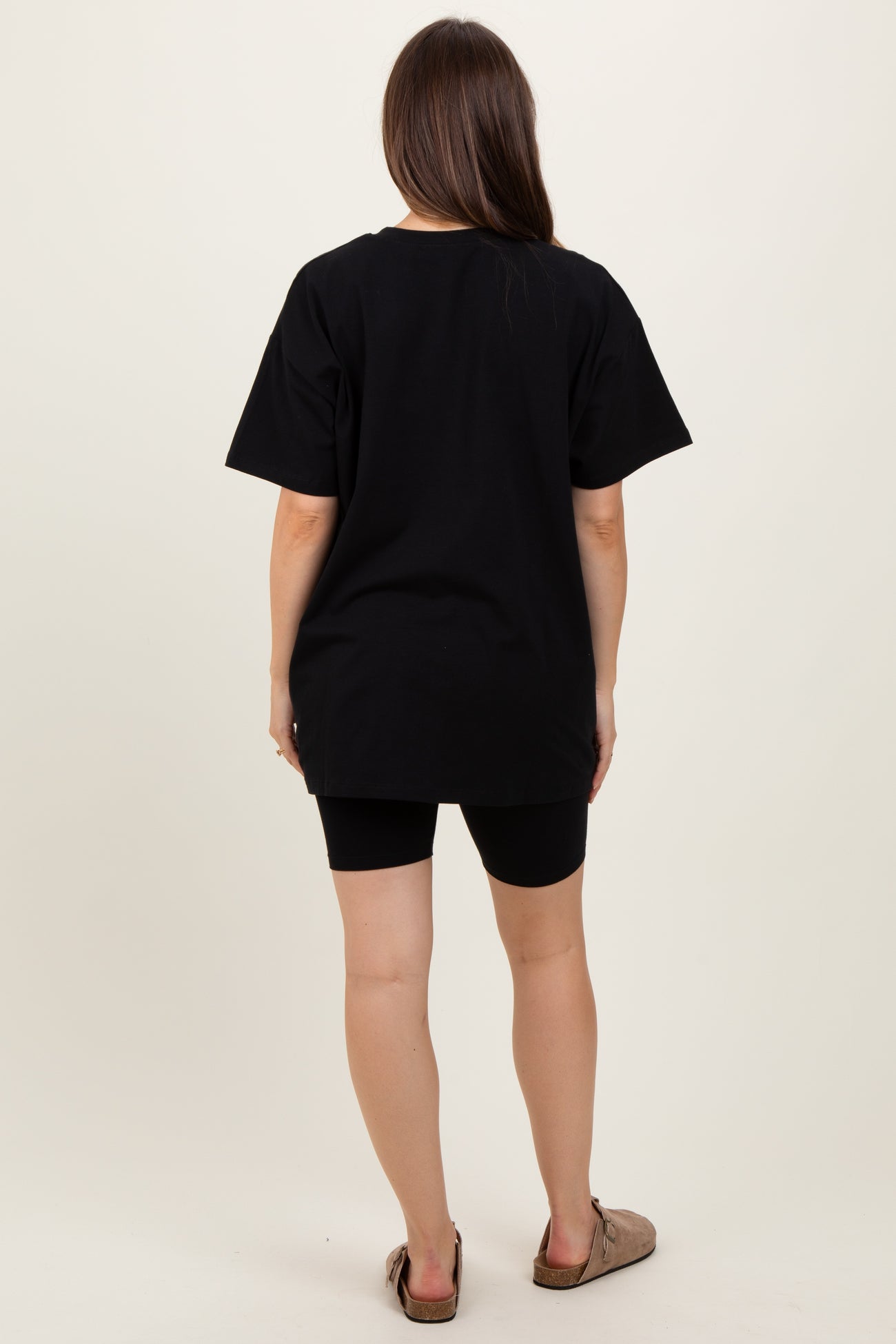 woman wearing a black oversized maternity t-shirt and black bike shorts, showing a casual look from the back