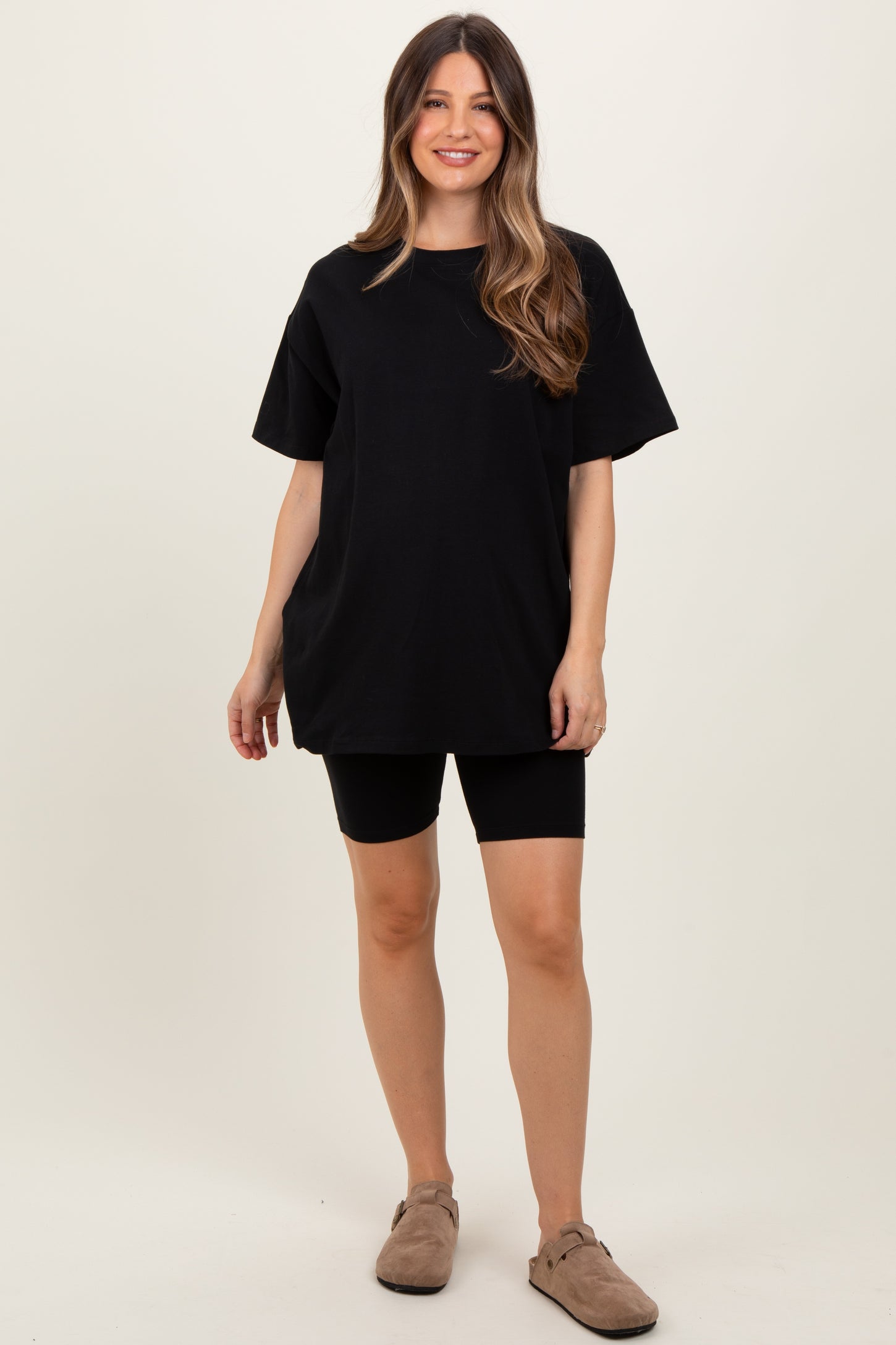 woman wearing a black oversized t-shirt and black bike shorts, styled for maternity wear