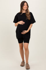 woman wearing a black oversized t-shirt and black bike shorts, showcasing her baby bump