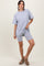 woman wearing a light gray oversized t-shirt and matching bike shorts, posing with one hand on her hip
