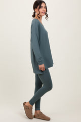woman wearing a teal oversized long sleeve top and matching leggings, styled with brown slip-on shoes