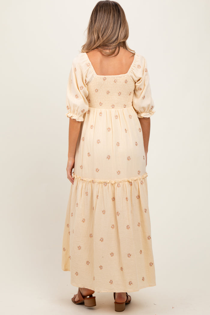 woman wearing a maternity wear yellow floral maxi dress with puff sleeves and a smocked back, showing a baby bump