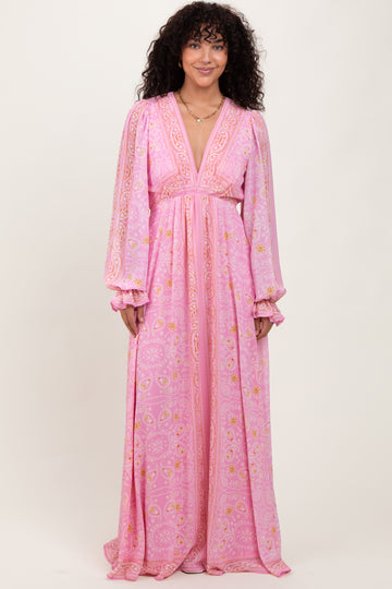 woman wearing a pink bohemian maxi dress with long sleeves and intricate patterns