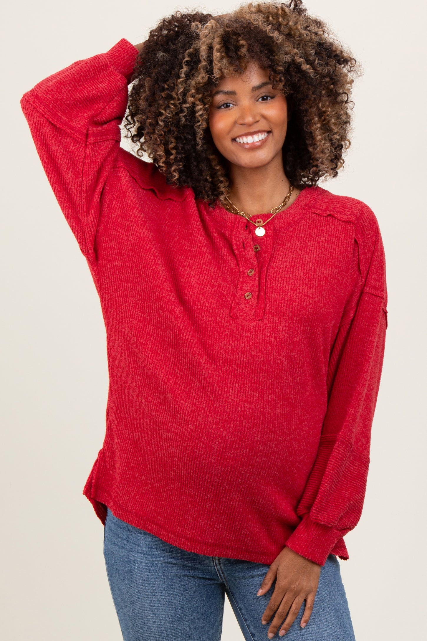 woman wearing a red maternity long sleeve button-up top with a relaxed fit and a baby bump visible