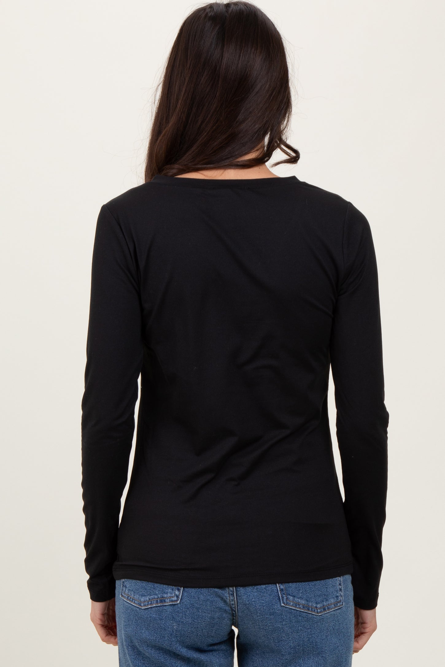 woman wearing a fitted black long sleeve top with a round neck, view from the back