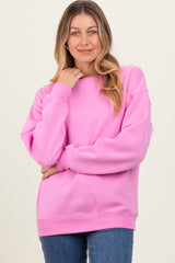 woman wearing a soft pink oversized sweatshirt with long sleeves and a relaxed fit, styled with blue jeans