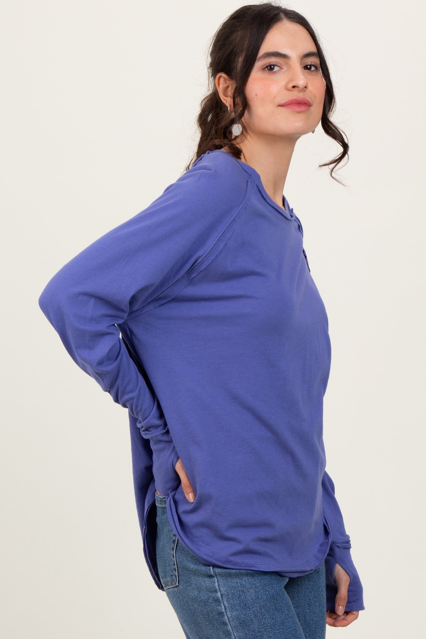 woman wearing a purple long sleeve casual top with a relaxed fit and side slits, paired with blue jeans