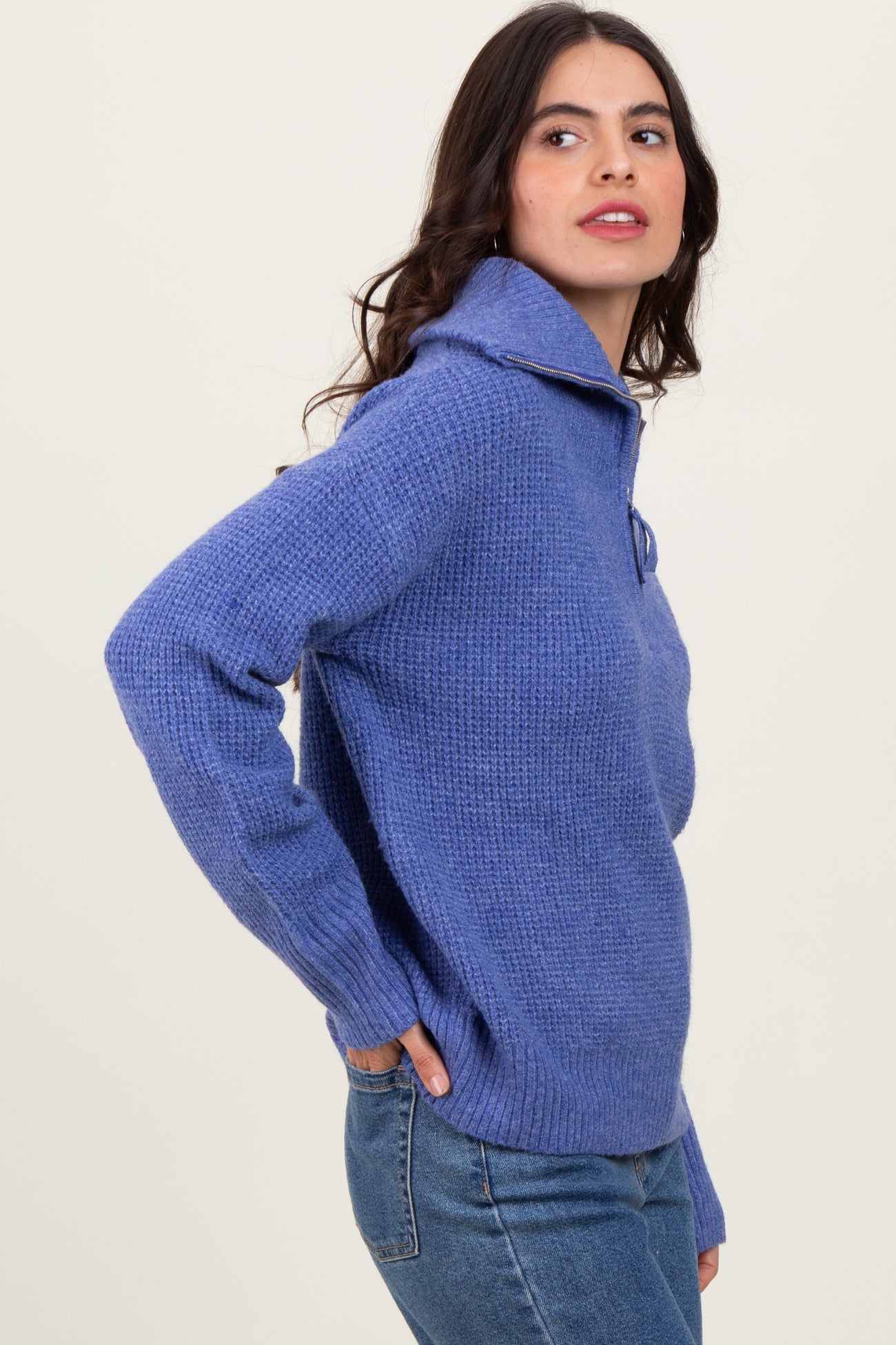 woman wearing a light purple knit pullover sweater with a folded collar and side pockets, paired with jeans