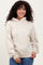 woman wearing a beige oversized hoodie with drawstrings and front pocket, styled with blue jeans