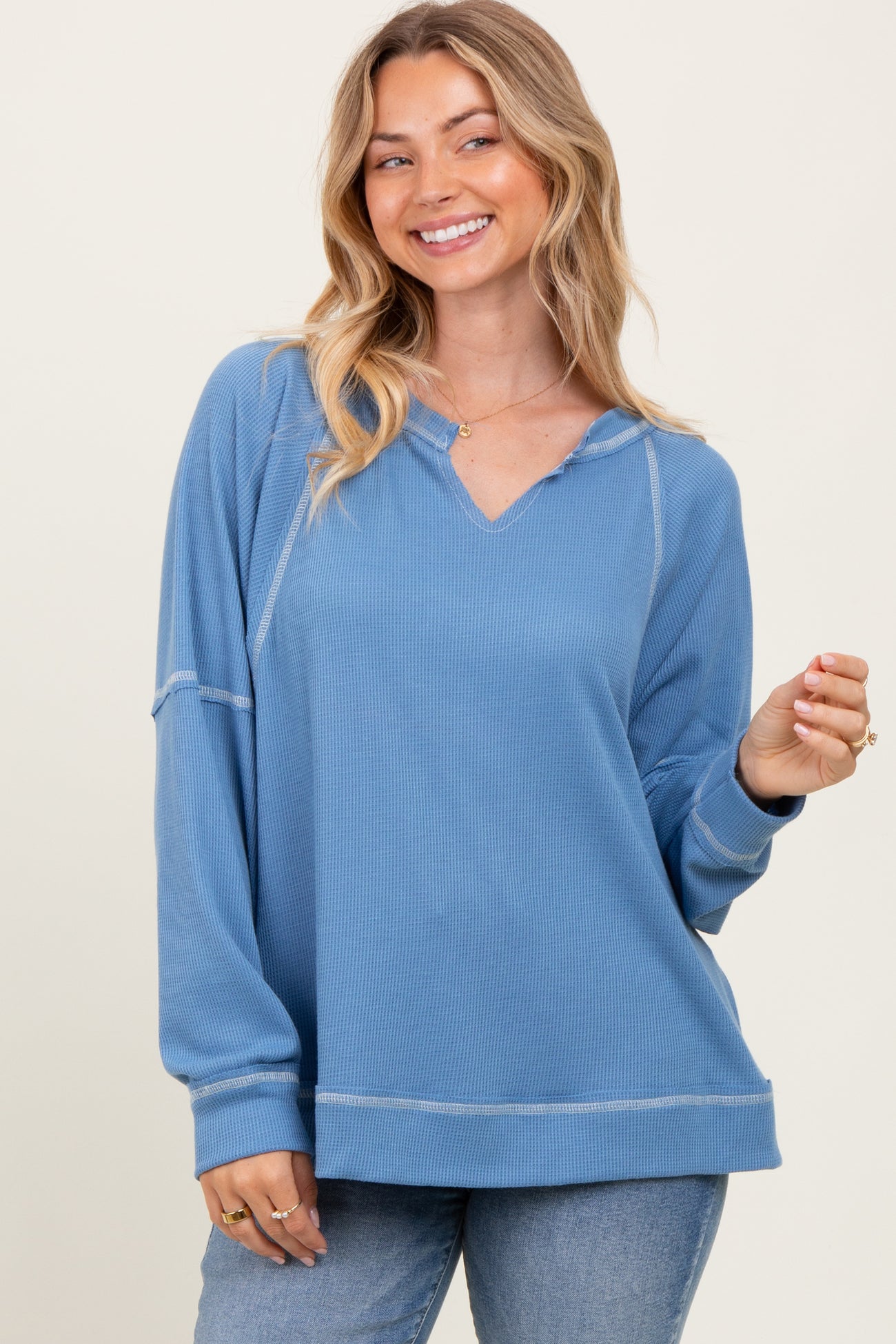 woman wearing a light blue long sleeve pullover with a hood and relaxed fit, smiling at the camera
