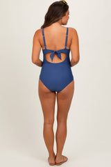 woman wearing a blue maternity swimsuit with a tie back detail and a modest cut, showing a baby bump