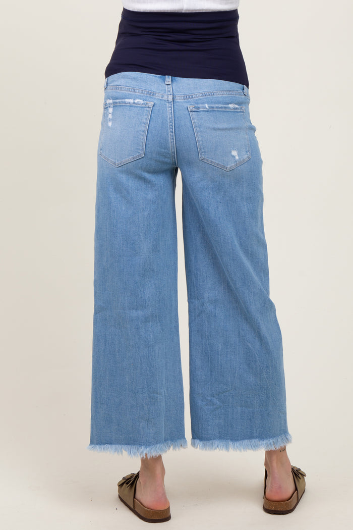 woman wearing light blue maternity wide-leg jeans with a distressed hem, showing a baby bump from behind