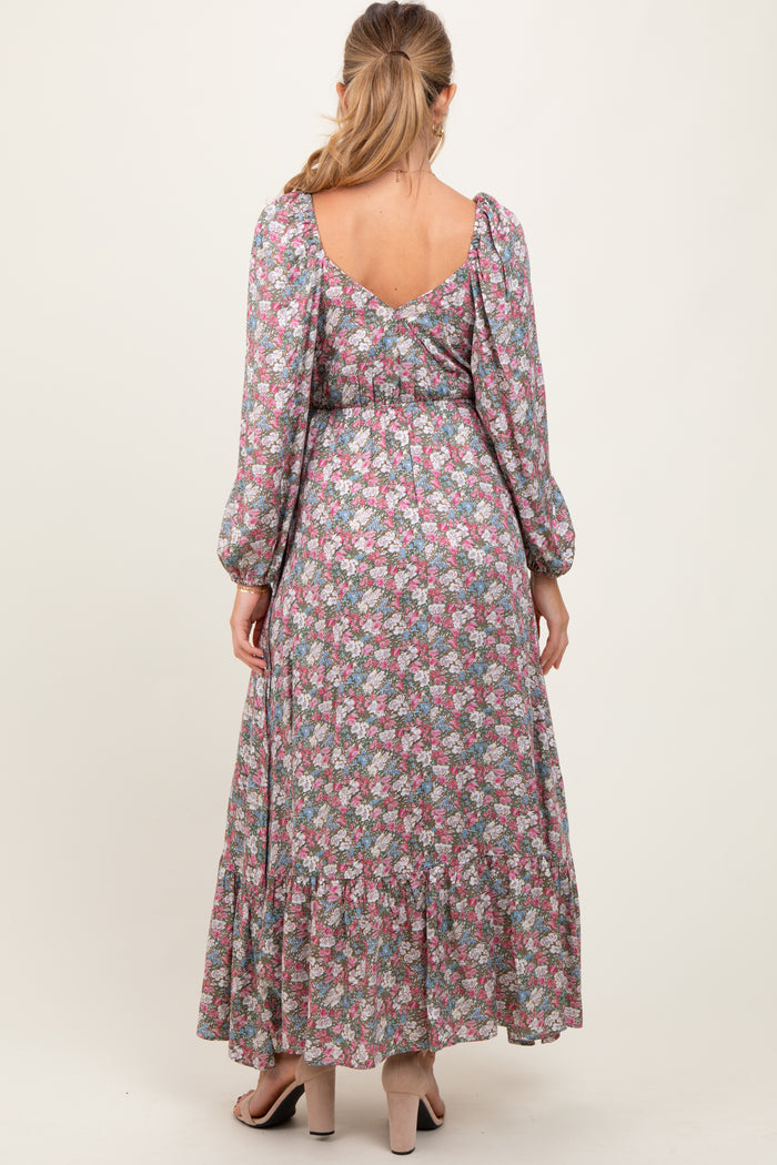 woman wearing a floral maternity maxi dress with puff sleeves and a tiered skirt, showcasing a visible baby bump