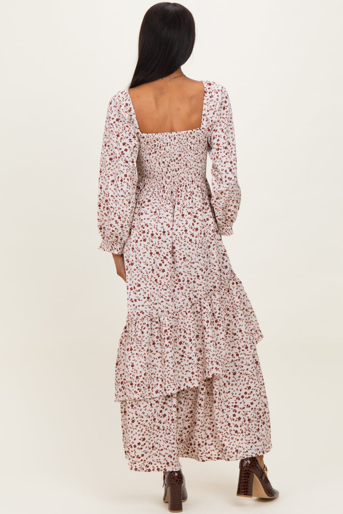 woman wearing a back view of a cream floral maxi dress with puff sleeves and tiered ruffles