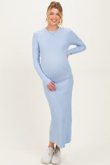 woman wearing a light blue ribbed maternity maxi dress and holding her baby bump
