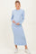 woman wearing a light blue ribbed maternity dress with long sleeves and a visible baby bump, holding her belly