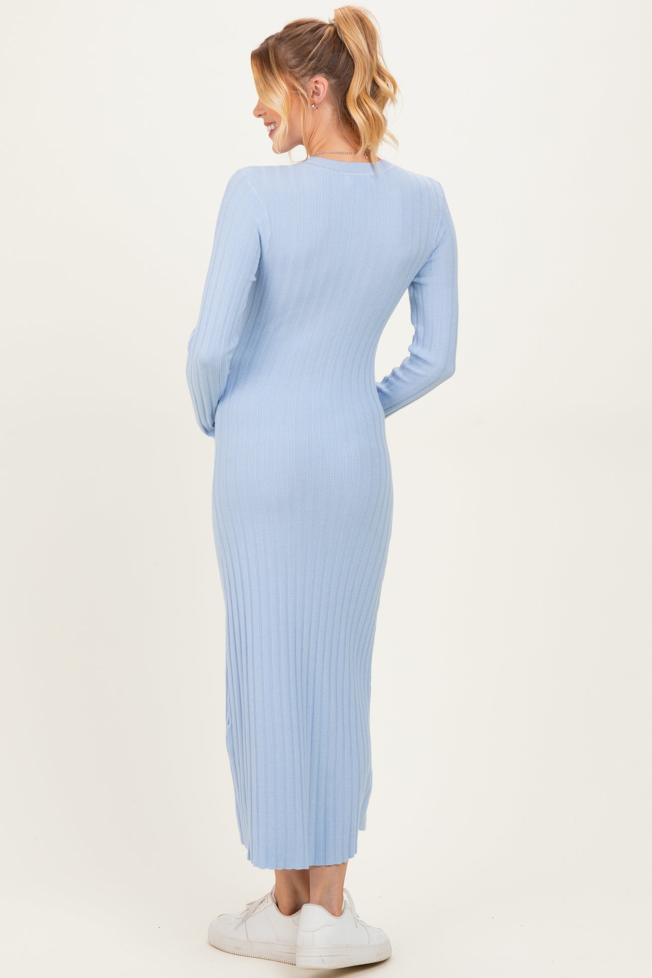 woman wearing a light blue ribbed maternity maxi dress, showing a fitted silhouette from the back