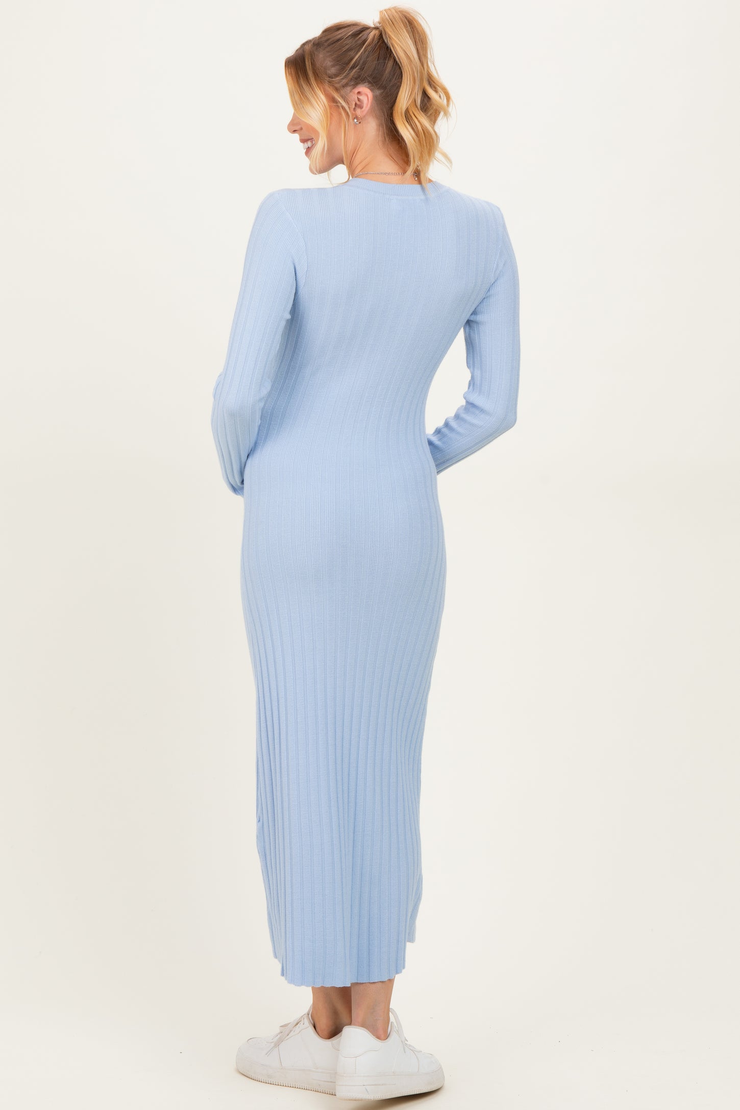 woman wearing a light blue ribbed maternity maxi dress, showing a fitted silhouette from the back
