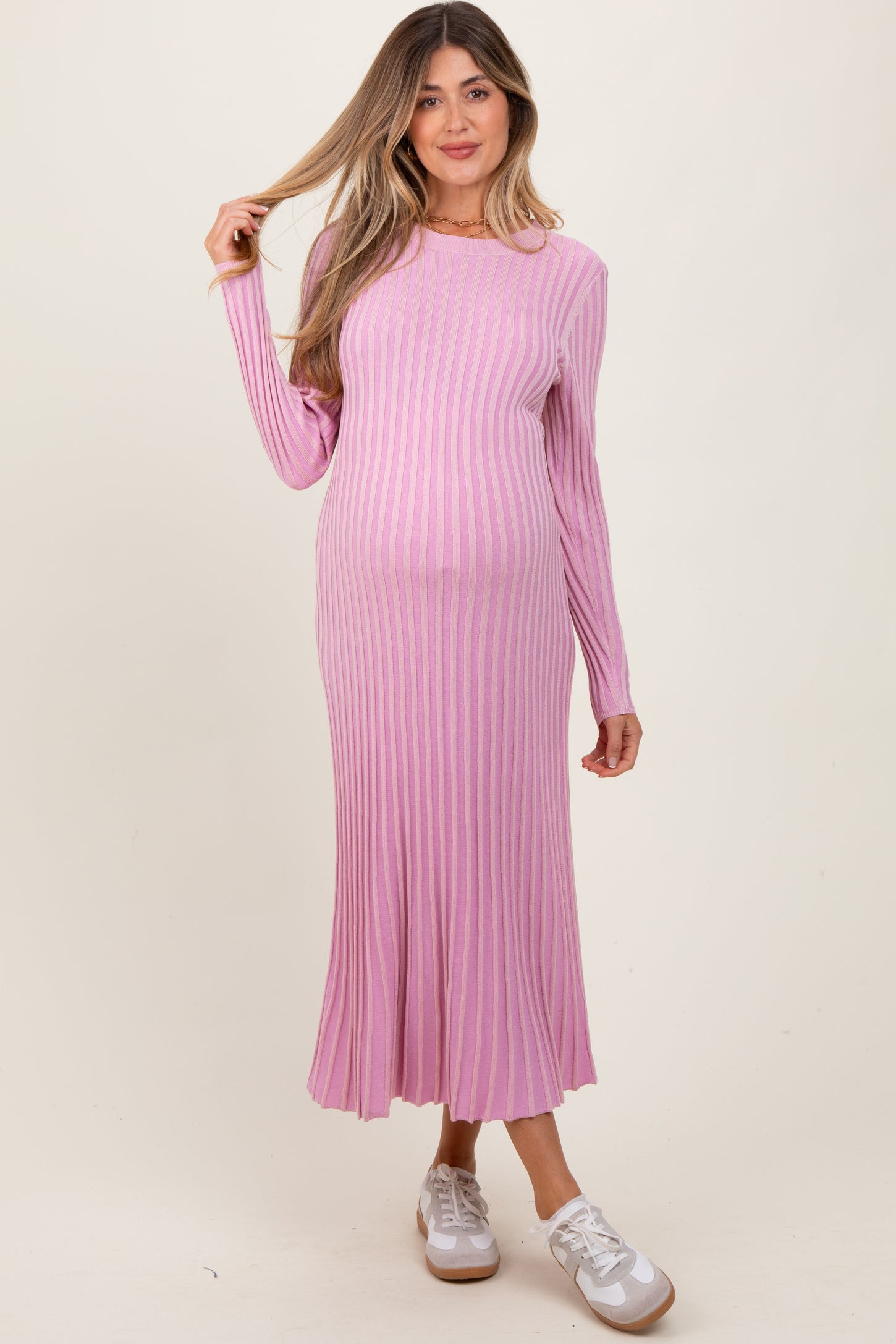 woman wearing a long sleeve light pink ribbed maternity dress with a baby bump visible