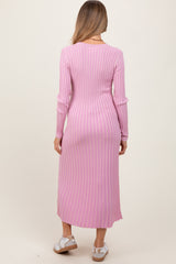 woman wearing a long pink striped maternity dress, showing the back view with fitted silhouette and split detail at the hem