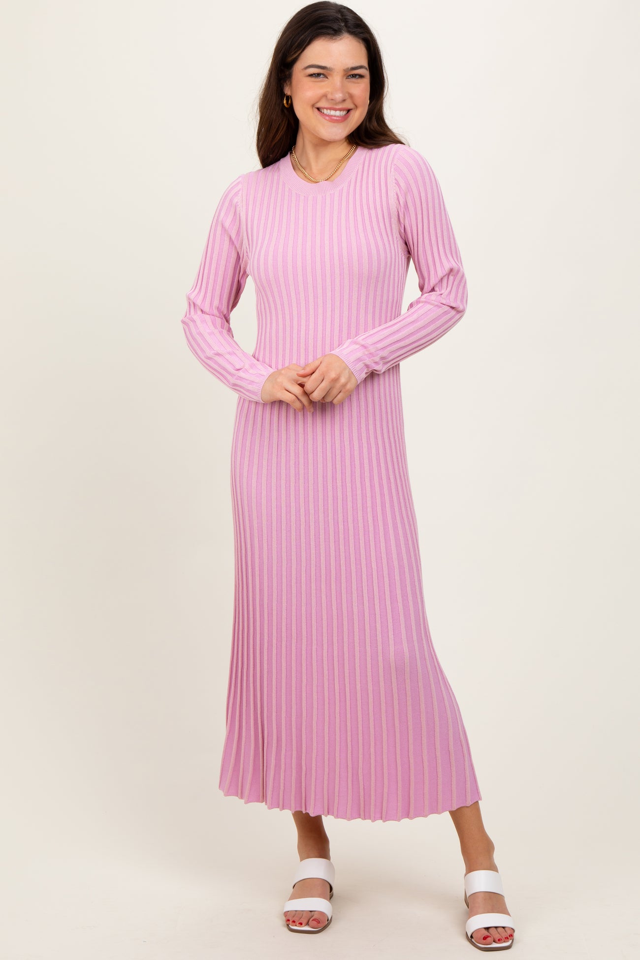 woman wearing a light pink ribbed long sleeve maxi dress with a flared hem and white sandals