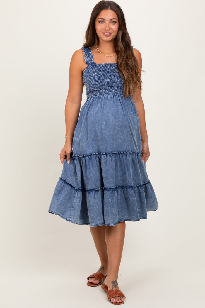 woman wearing a denim maternity dress with a smocked bodice and tiered skirt, styled casually with sandals