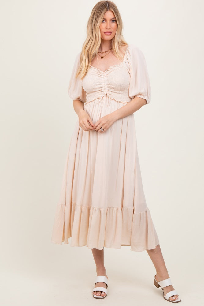 woman wearing a light peach puff sleeve maxi dress with a smocked bodice and ruffled hem