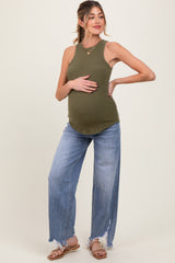 woman wearing a dark green ribbed maternity tank top and light wash wide-leg jeans, highlighting her baby bump