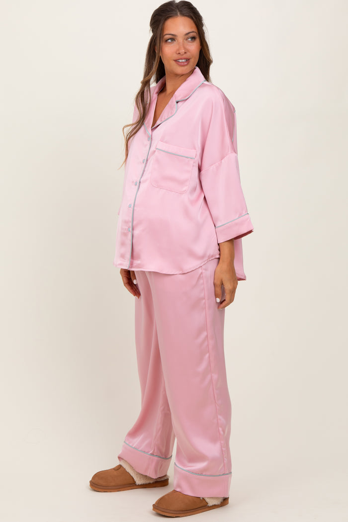 woman wearing a pink satin maternity pajama set with a button-up top and loose-fitting pants, showing her baby bump