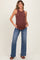 woman wearing a brown ribbed maternity tank top and blue flared jeans, showcasing her baby bump