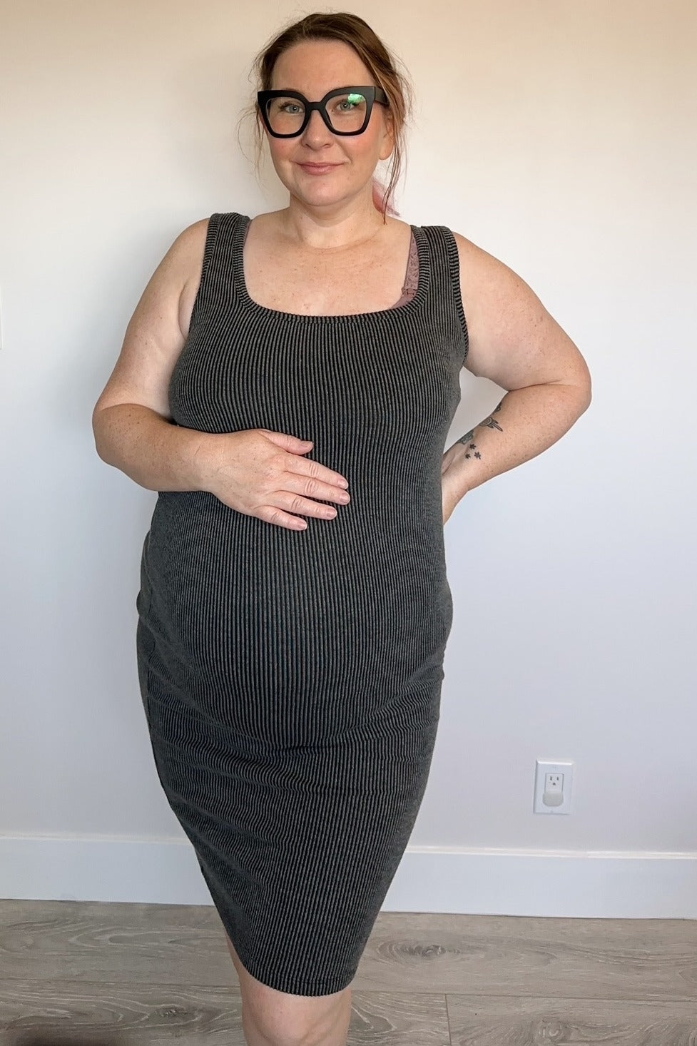 woman wearing a grey ribbed maternity dress and holding her baby bump