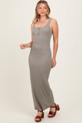 woman wearing a striped sleeveless maxi dress with buttons, posing with a slight smile and wearing brown heeled sandals