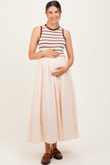 woman wearing a striped maternity tank top and a flowing midi skirt, cradling her baby bump