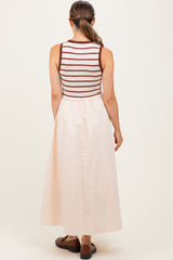 woman wearing a striped sleeveless maternity dress with a peach maxi skirt from the back
