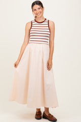 woman wearing a striped sleeveless maternity dress with a fitted top and a flowy peach skirt, smiling and posing
